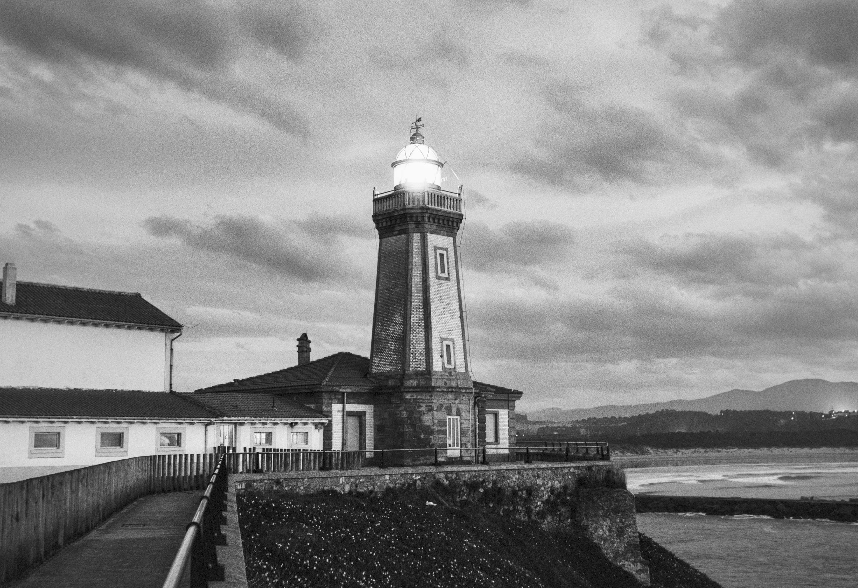 San Juan Lighthouse in Avilés at dusk, with its beacon lit over the coastline.
