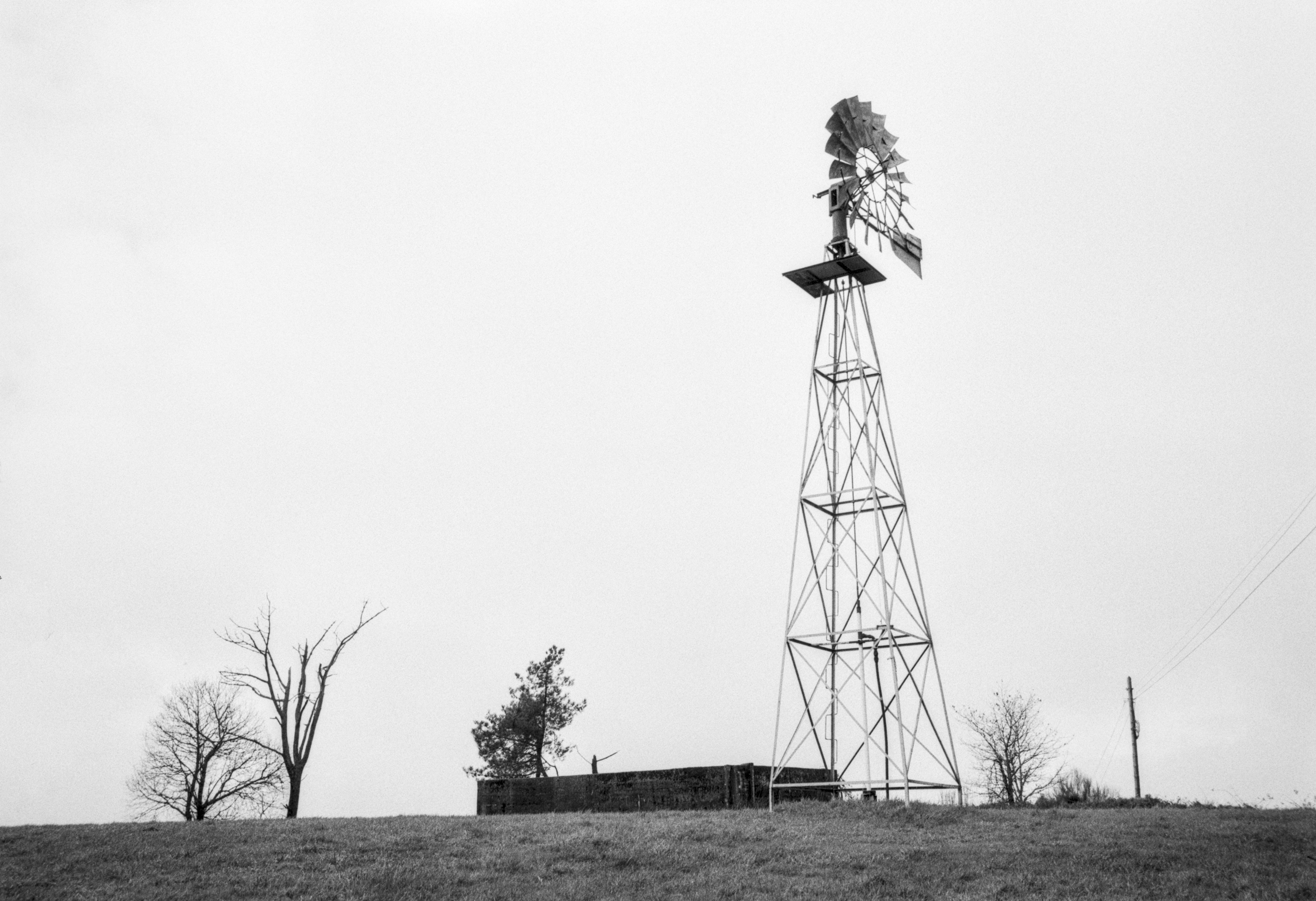 A tall metal windmill standing alone on a hill in Dozón.