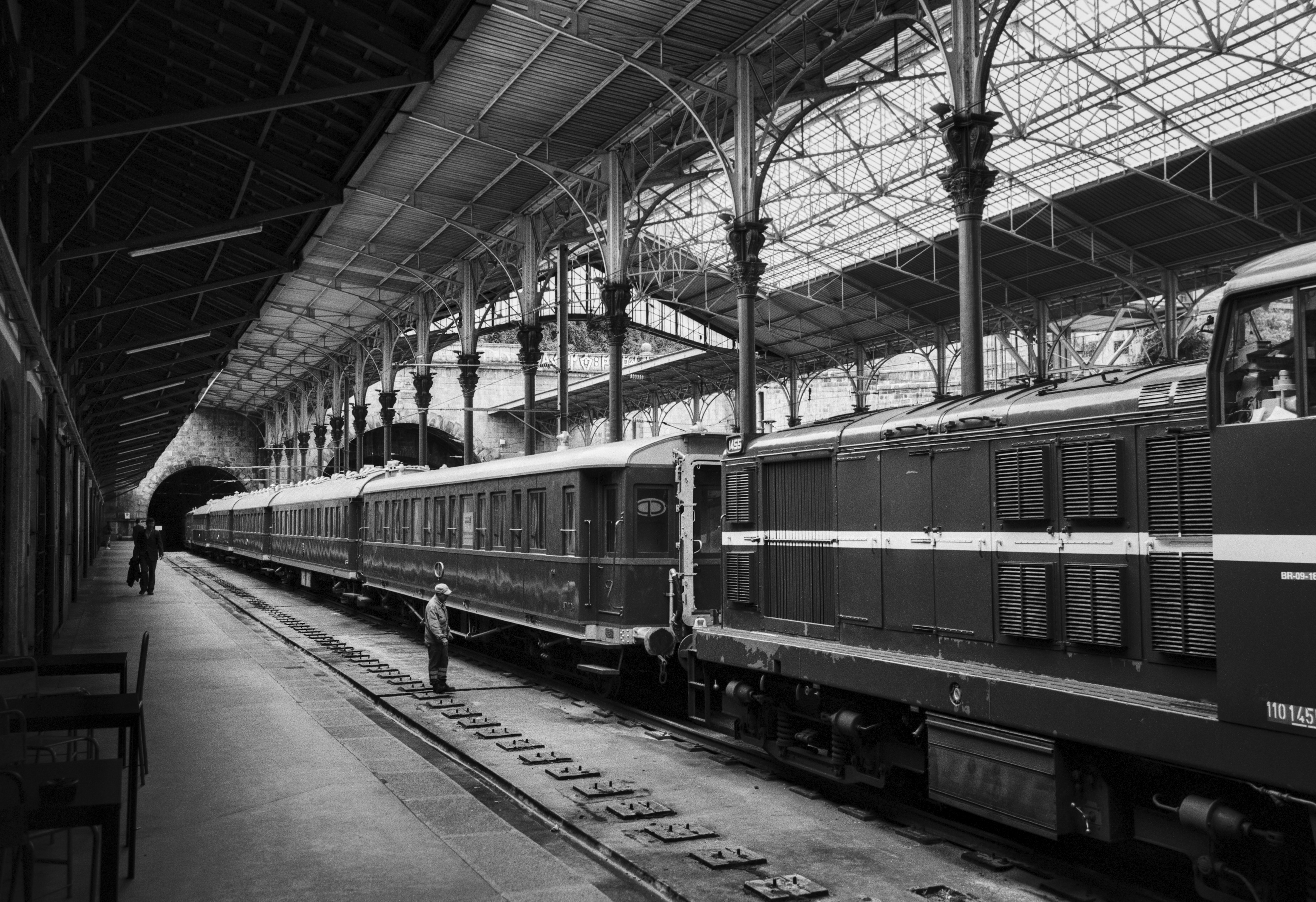 Interior view of Porto’s São Bento station, with vintage carriages and iron columns under the glass roof.