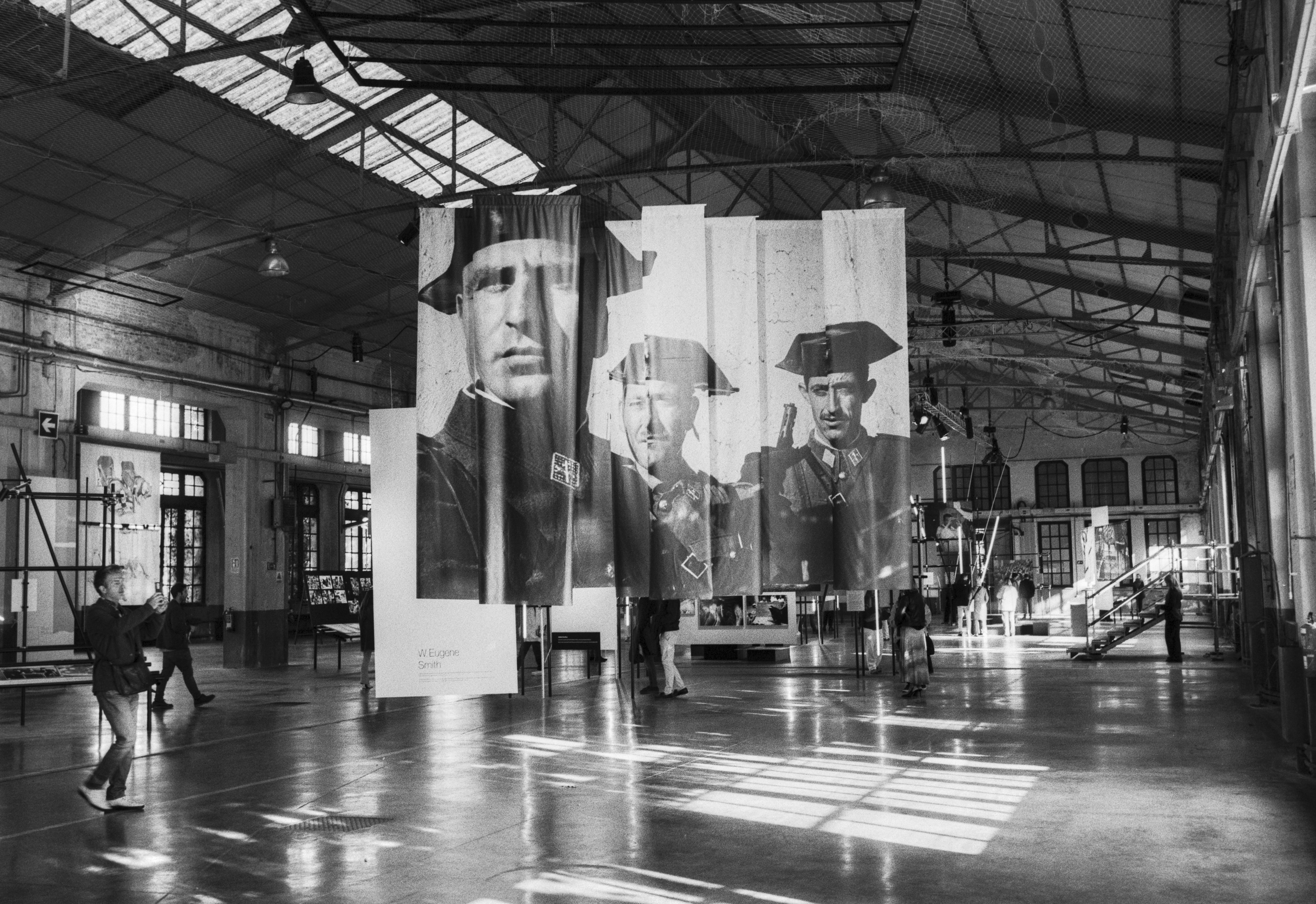 Visitors walking through a Magnum photography exhibition in Oviedo, with large portraits hanging inside an industrial hall.