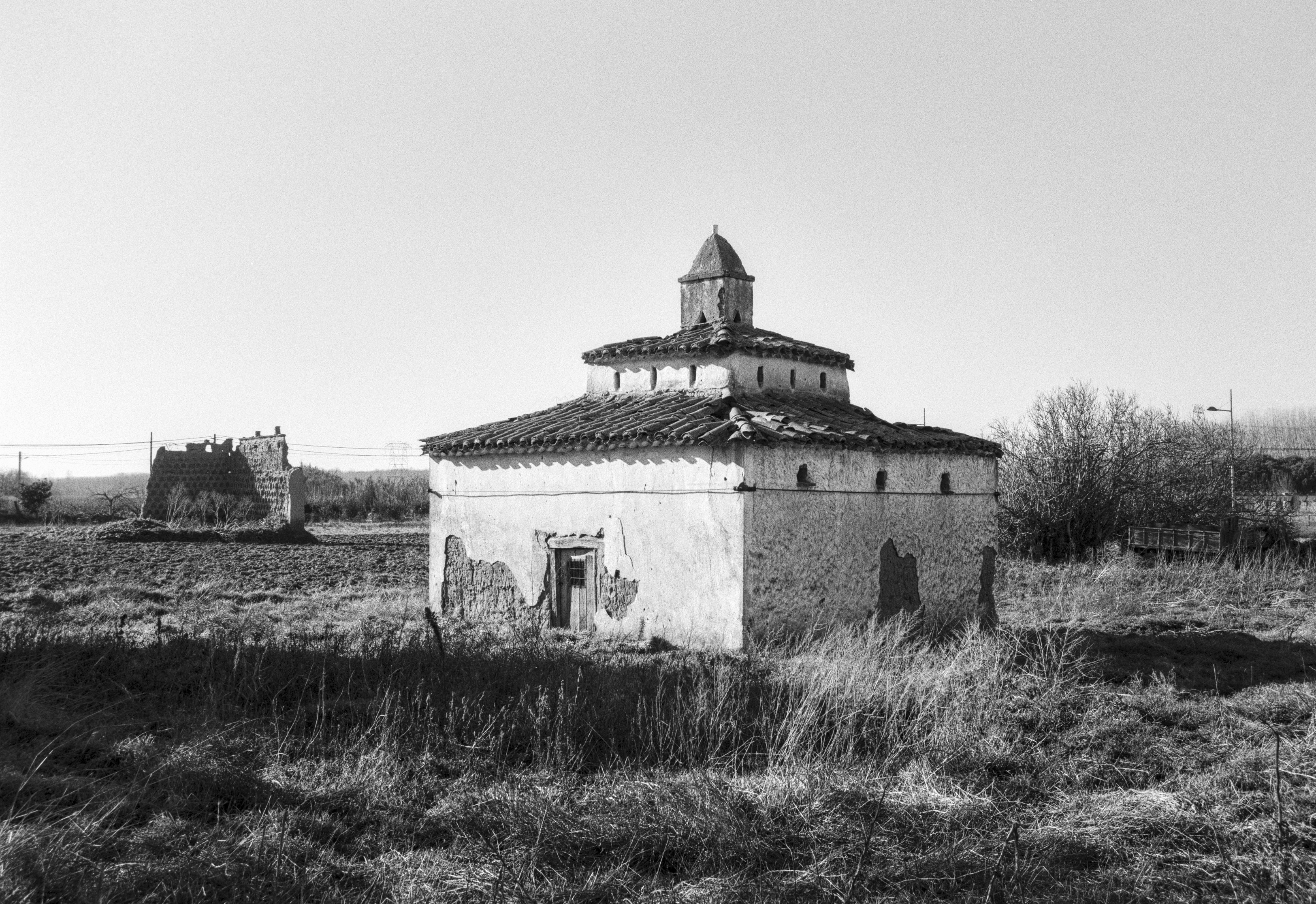 An old dovecote standing in an open field, weathered and partially crumbling.
